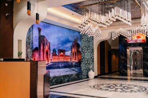 a lobby with a painting on the wall and chandeliers at Hanzade Palace in Samarkand