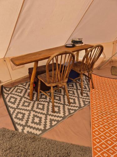 a wooden table and two chairs in a tent at Lyng Farm Campsite in Brisley