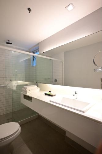 a bathroom with a sink and a toilet and a mirror at Hotel Luzeiros Recife in Recife