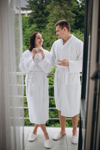 a man and woman in white robes looking at their cell phones at NACHIKU Bukovel Resort & SPA in Palyanytsya