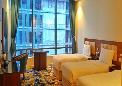 a hotel room with two beds and a large window at المهاجر للشقق المخدومة بالكورنيش in Jeddah