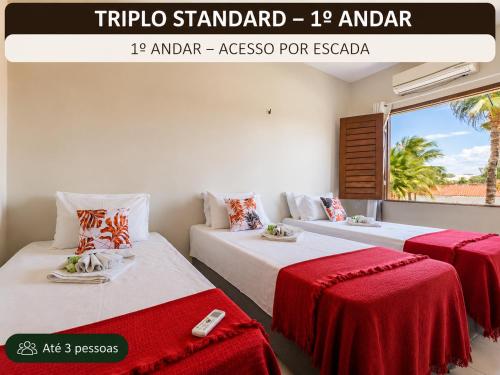 two beds in a room with red and white sheets at Pousada Sunrise Beach in Cumbuco