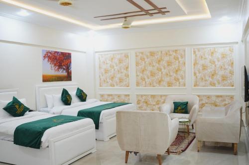 a bedroom with two beds and a couch and chairs at Pc Inn Executive Class Hotel in Sukkur