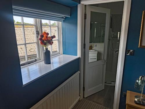 a blue bathroom with a vase of flowers in a window at The Red Lion Hotel in Oakford