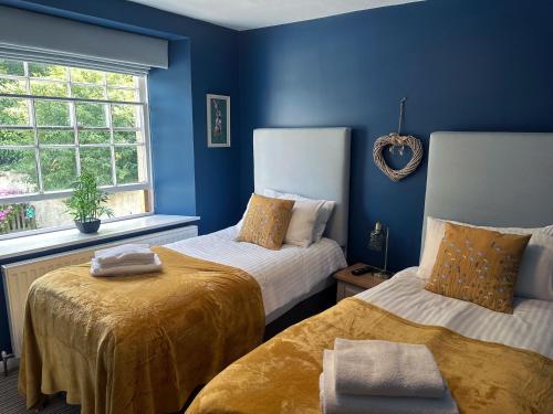 a blue room with two beds and a window at The Red Lion Hotel in Oakford