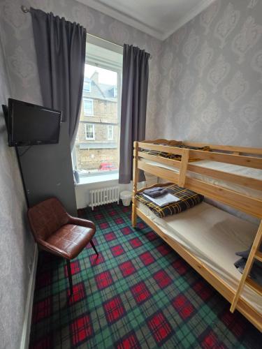a bedroom with bunk beds and a tv and a chair at IVY House in Edinburgh