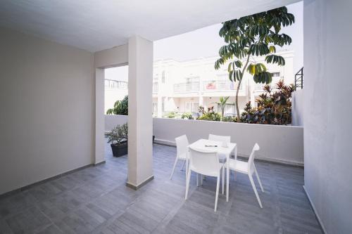 a white dining room with a table and chairs at Los Olivos Beach Resort in Adeje