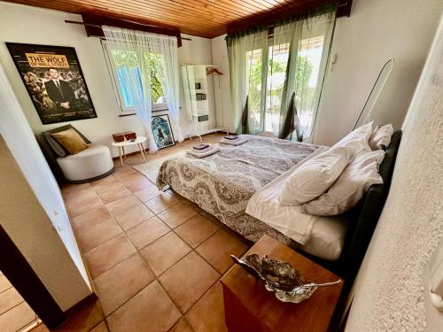 a bedroom with a bed and a chair and windows at Villa Lake View in Grandvaux