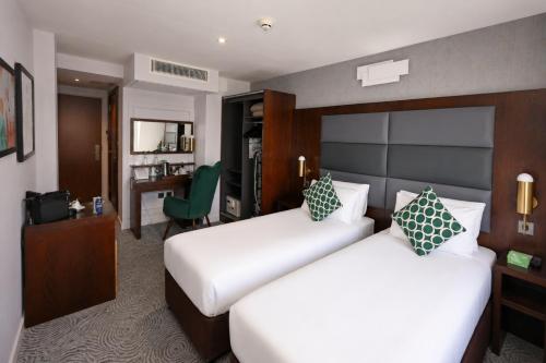 a hotel room with two beds and a desk at Mercure London Paddington Hotel in London