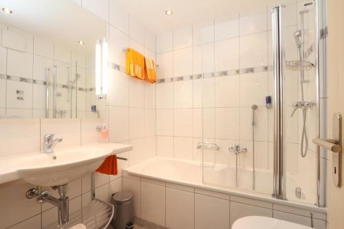 a bathroom with a tub and a sink and a shower at Appartements Feehof in Saas-Fee