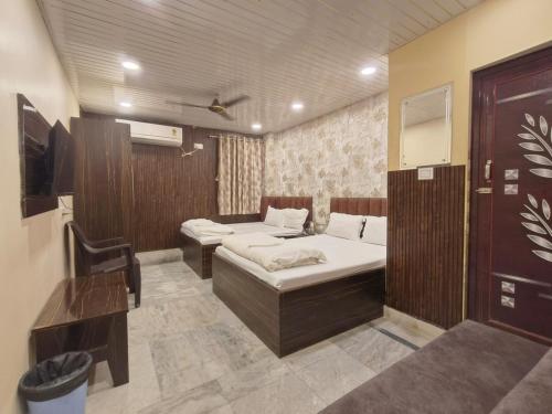 a room with two beds and a desk in it at Hotel Royal Palace in Kolkata