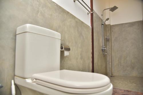 a white toilet in a bathroom with a shower at Buddika Safari & Resort in Udawalawe