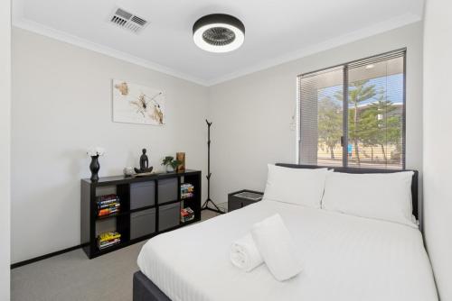 a bedroom with a white bed and a window at Drift at Shorehaven Coast in Alkimos