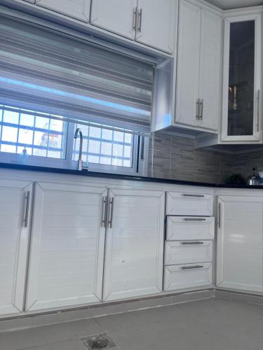 a white kitchen with white cabinets and a window at Ali Building in Wadi Musa