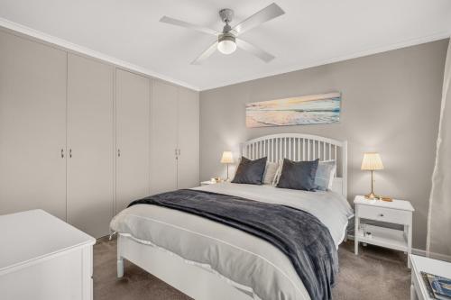 a white bedroom with a bed and a ceiling fan at Grace Cottage, Barossa Valley in Lights Pass