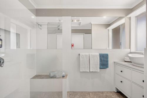 a white bathroom with a sink and a mirror at Grace Cottage, Barossa Valley in Lights Pass