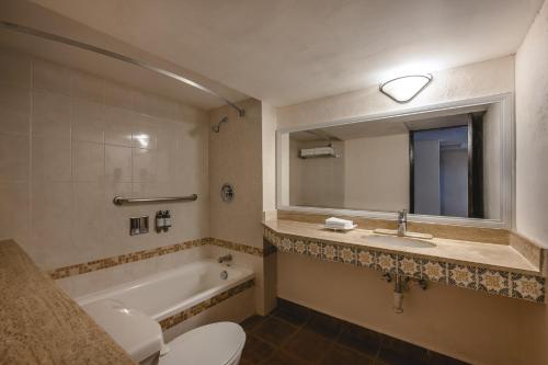 a bathroom with a toilet and a sink and a tub at Gamma Merida El Castellano in Mérida