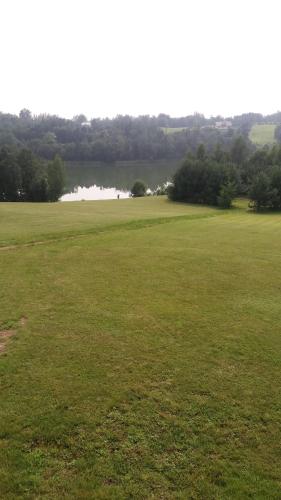 a large green field with a lake in the distance at Country Houses Vidų Sodyba in Utena