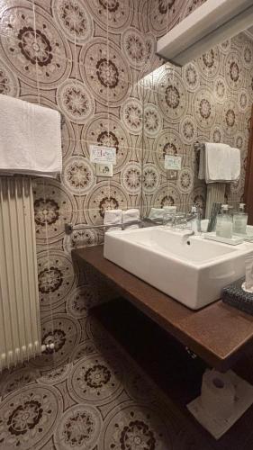 a bathroom with a white sink and a wall at Pension Hauenstein in Lagundo