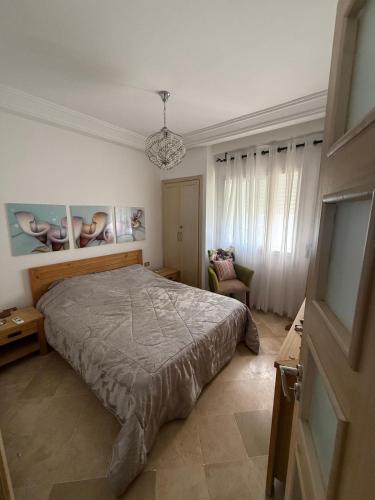 a bedroom with a bed and a chandelier at Les pieds dans l eau, résidence Nadine in Hammam Sousse