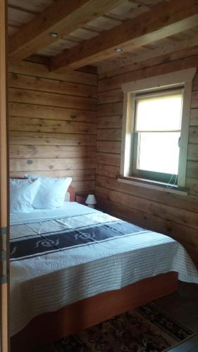 a bed in a wooden room with a window at Country Houses Vidų Sodyba in Utena
