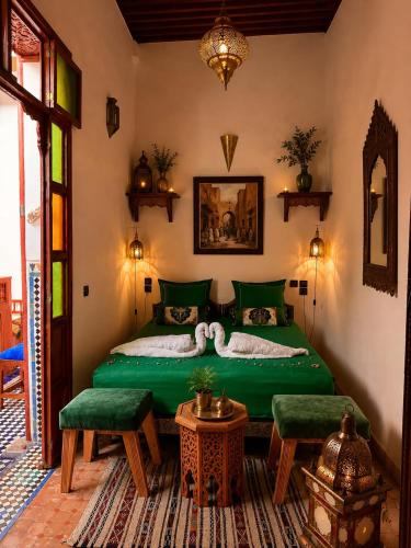a bedroom with a green bed and two green chairs at Riad Hamad Tijani in Fez