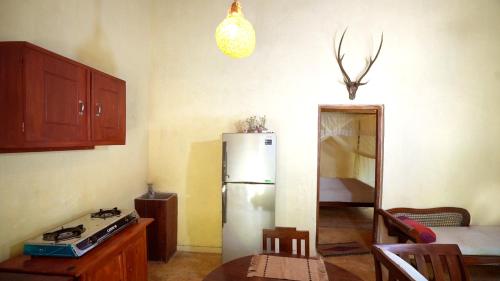 a kitchen with a refrigerator and a table in it at Kethbima Agri Cottage in Amunugama