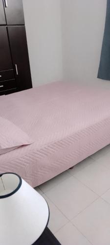 a bed with a white mattress and a white table at Departamento luminoso y amplio in San Antonio de Areco