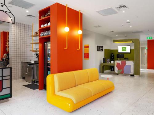 a yellow couch sitting in a store lobby at ibis Styles Old Tbilisi in Tbilisi City