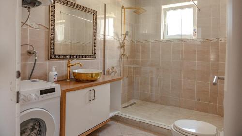 a bathroom with a shower and a sink and a washing machine at Lux Stays in Prishtinë