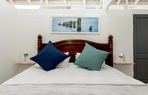 a bedroom with a bed with two blue pillows at Kai Cottage in Bergvliet