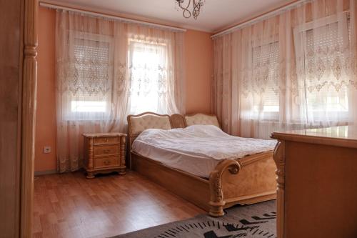 a bedroom with a bed and a window with curtains at Lux Stays in Prishtinë
