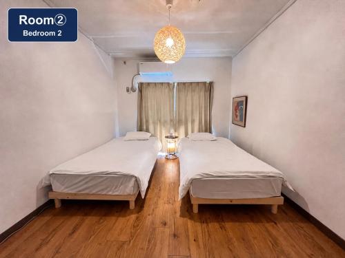 two beds in a hospital room with a window at 北浜703 3ベッドルーム貸切 高松港近く 最大6名 in Takamatsu