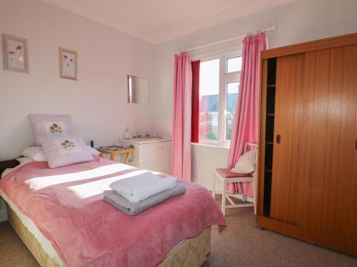 a bedroom with a bed and a window with pink curtains at Sylvian in Bexhill