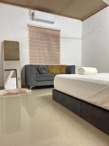 a bedroom with a bed and a couch in it at Rumah Singgah in Bentong