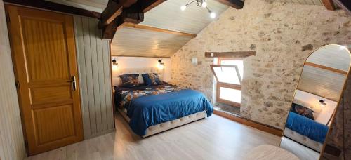a bedroom with a bed with blue sheets and a mirror at Gîte de l'Aiguillier in Castelnau-de-Montratier