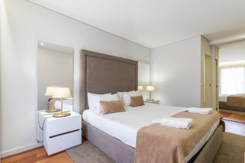 a white bedroom with a large bed and two lamps at Porto & Douro Vista Apartments by Inviting in Valbom