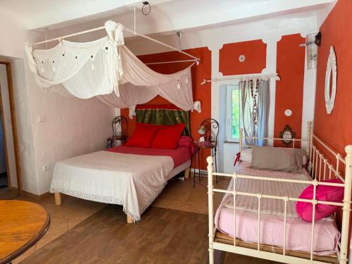 a bedroom with two beds with red walls and white curtains at Le Mas Sylva in La Barriére