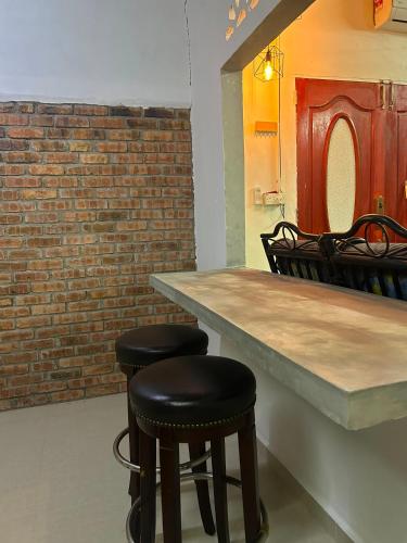 a bar with black stools next to a brick wall at Rumah Singgah in Bentong