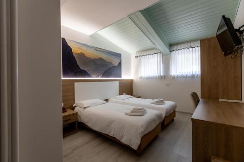 a bedroom with two beds and a painting on the wall at Hotel Venezia in Rocca Pietore