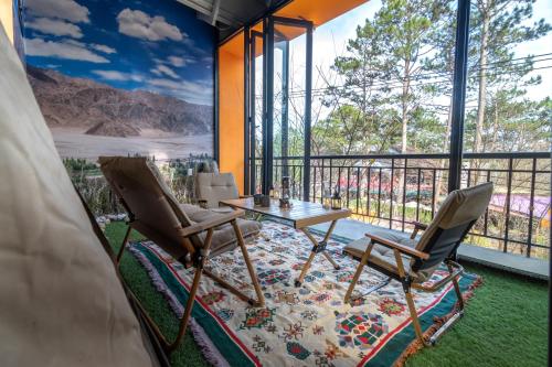 a room with a table and two chairs and a balcony at De Vivre Homestay Măng Đen in Kon Von Kla