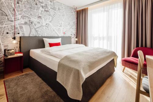 a hotel room with a bed and a red chair at IntercityHotel Braunschweig in Braunschweig
