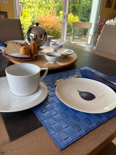 a table with plates and cups and bread on it at Chambre d'hôtes les Galets Bleus in La Rochelle