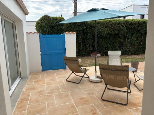 a patio with two chairs and a table with an umbrella at Chambre d'hôtes les Galets Bleus in La Rochelle