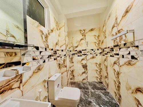 a bathroom with marble walls and a toilet and sink at Ayomal Beach Paradise in Galle
