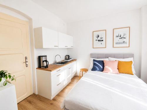 a white bedroom with a bed and a kitchen at Villa Medica in Kraslice