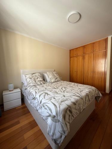 a bedroom with a bed and a wooden cabinet at Machico Village Apartment - Private terrace & car park in Machico