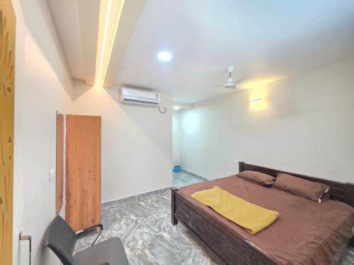 a bedroom with a bed with a yellow blanket on it at AJS Elite Rooms in Nagari