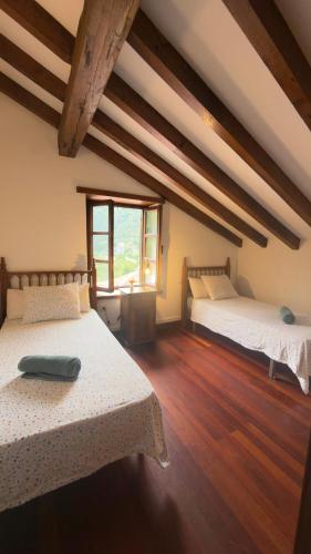 two beds in a room with wooden floors at Explora Picos de Europa in Cosgaya