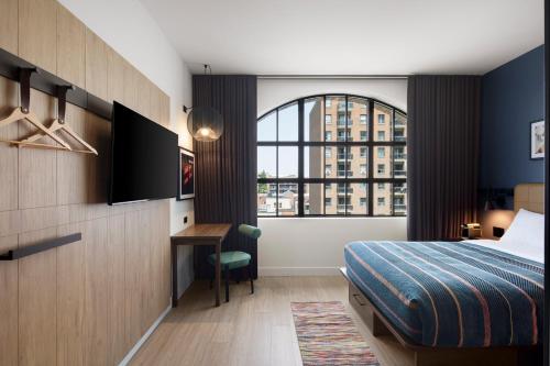 a bedroom with a bed and a desk and a window at New Moxy Ottawa Downtown in Ottawa